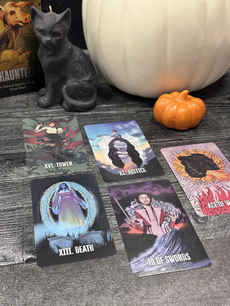 Haunted A Cursed Appalachian tarot deck cards featuring folklore from West Virginia, Eastern Ohio, and Pennsylvania. Five cards Laye out including the Tower, Justice, Death, 10 of swords, and ace of wands